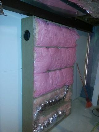 Packing the cavity around the run. The insulation is not filler; it is the working part. Every reflection off it costs the sound something and costs the airflow nothing.