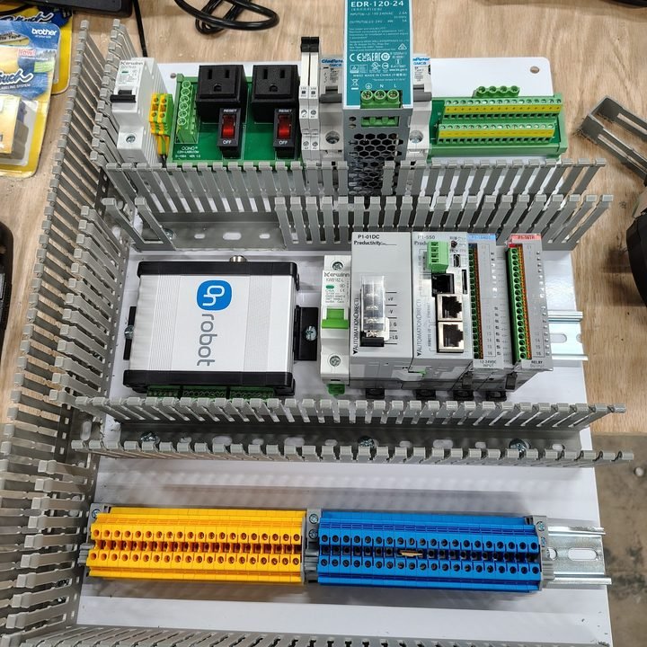 Backplate populated. Terminal blocks color-coded, network switch centered, wire duct sized for the harness that hasn't been run yet.