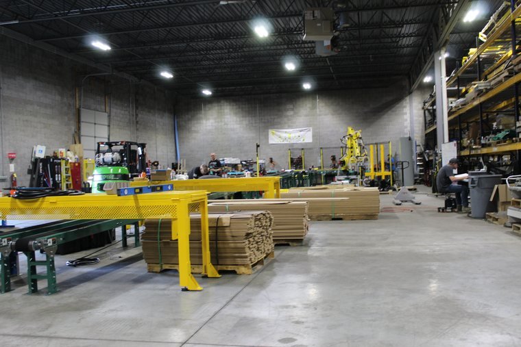 Gantry over the pack-out. Product stacked to the ceiling because that is what running well looks like.